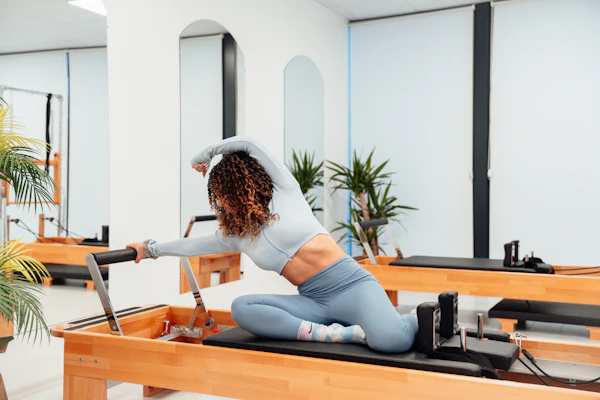 Instructor on a reformer beside the studio plants