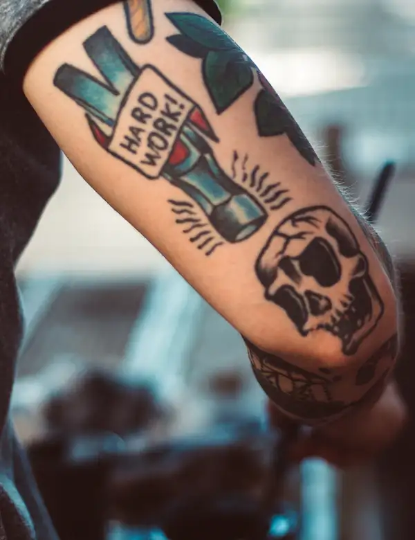 Traditional flash on a forearm: a bottle and a skull in bold colour