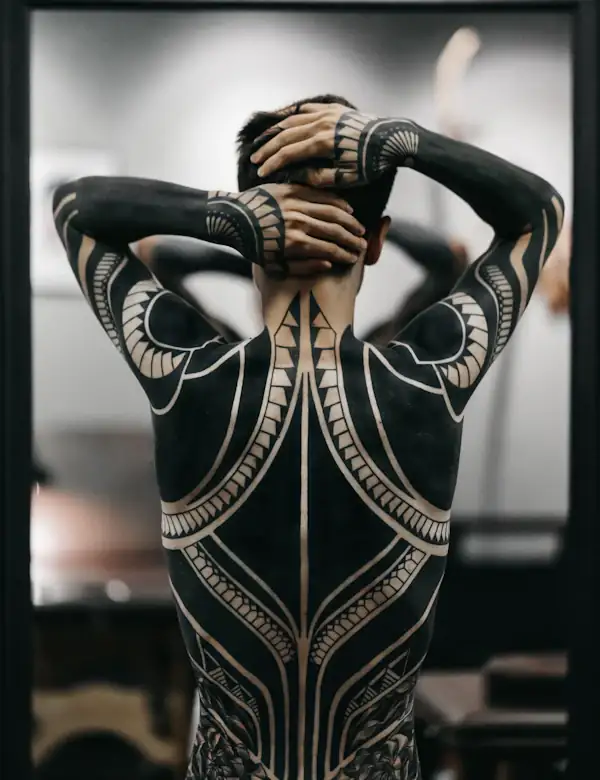 Bold geometric blackwork across a back and both arms