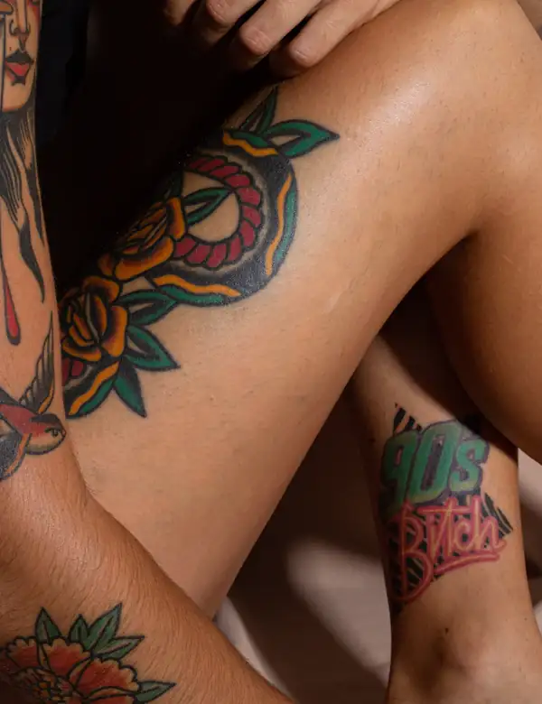 A traditional snake and rose in red, green and black on a leg