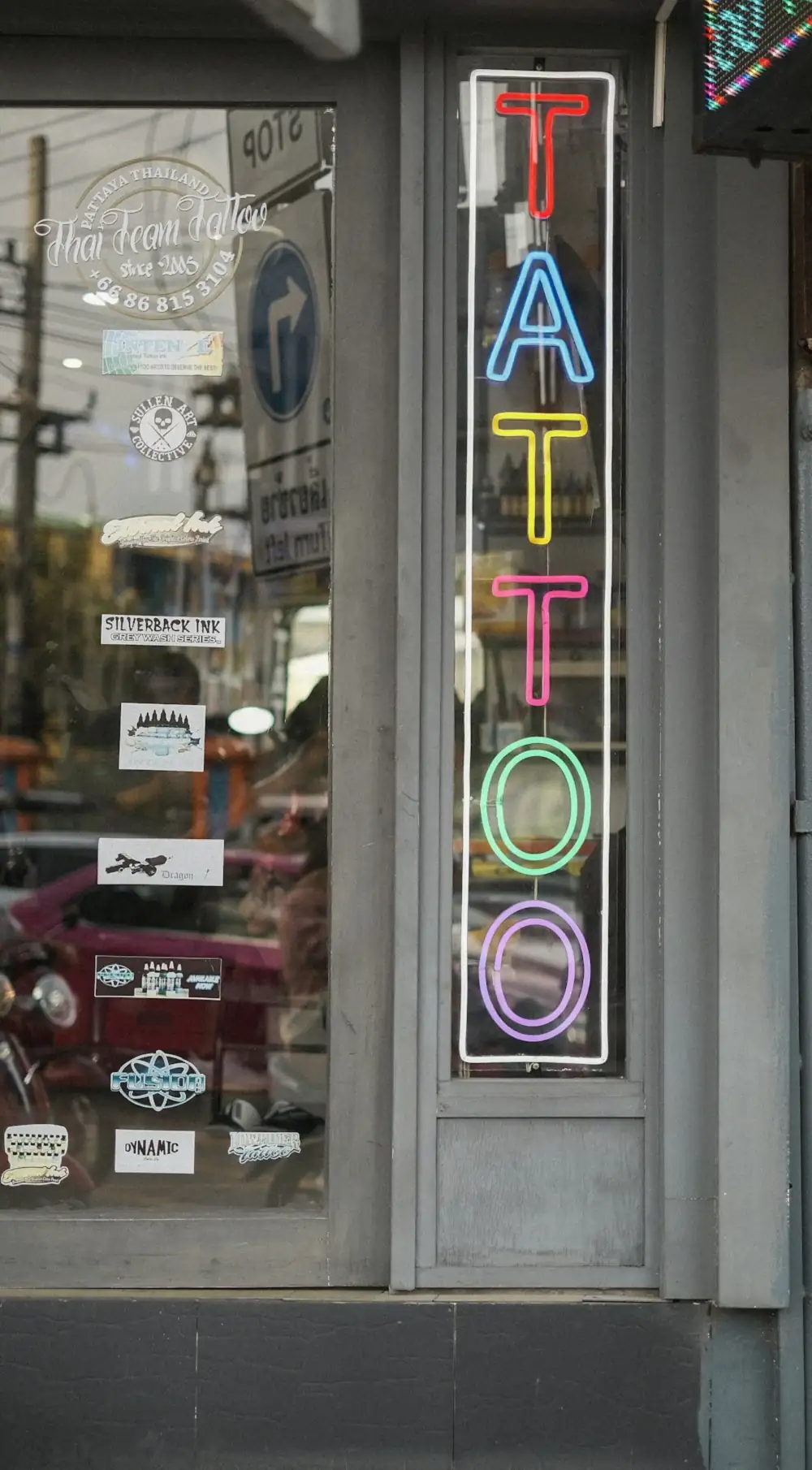 A neon tattoo sign in a studio window